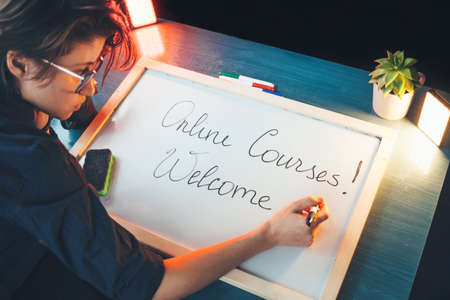 Caucasian woman is writing on a blackboard the greeting to online courses before start the lessonの写真素材