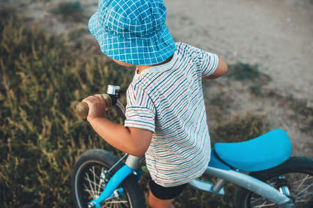 Upper view photo of a caucasian boy with blue hat riding a bike in the fieldの写真素材