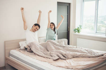 Caucasian couple stretching and yawning in bed early morning