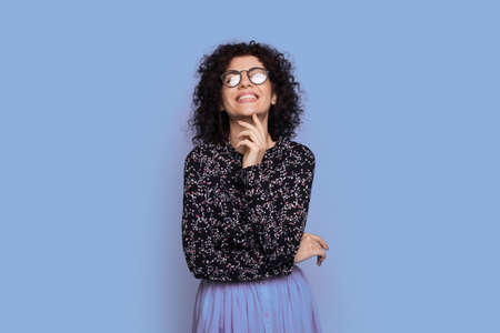 Monochrome photo of a caucasian curly haired woman with glasses and fashionable dress posing on a...