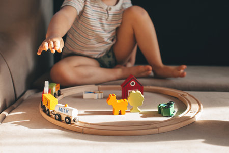 Close up photo of a boy playing with toy trains on a couch at homeの写真素材