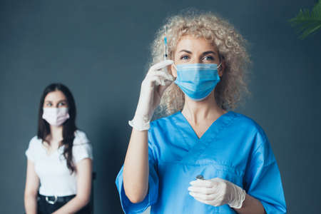 Doctor with syringe in hand and a patient near. Young girl getting vaccinated. Vaccination concept.の写真素材