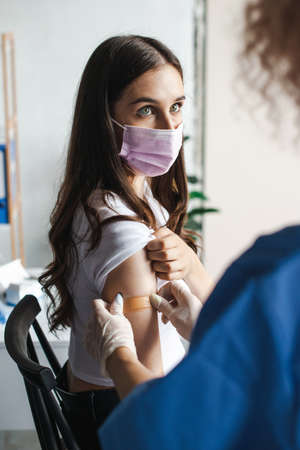 Woman doctor putting a vaccine and plaster. Vaccinated person. Virus protection. Doctor hand.