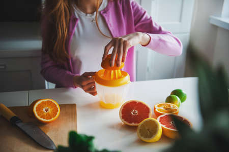 Woman squeezing oranges to make a natural citrus juice. Morning routine.の写真素材