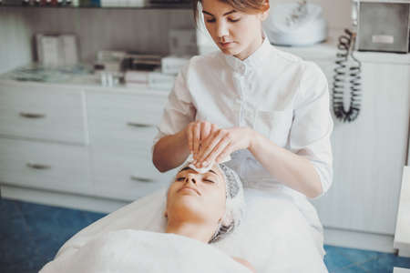 Cleaning forehead with facial sponges spa treatment. Professional service. Spa salonの写真素材