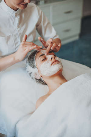 Close-up portraiat of womans hands applying rejuvenating facial mask and lifting massage.の写真素材