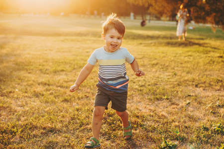 Caucasian boy runs along the field on camera. Childhood. Front view. Sunset.