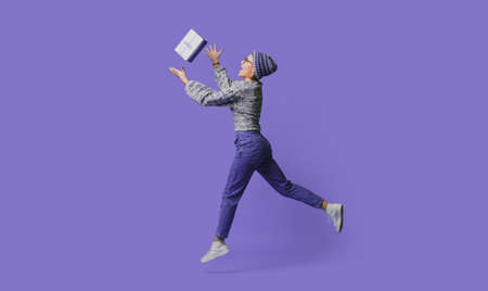 Full length side view photo of shocked caucasian woman wearing knitted hat and sweater catching gift...