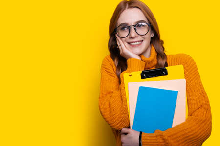 Excited caucasian student wearing eyeglasses holding books isolated over yellow background studio portrait. Free space. Empty space.の写真素材