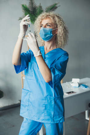 Curly doctor with syringe taking dose of Covid-19 vaccine for injection. Wearing gloves and medical...