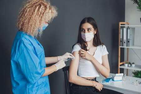 Doctor picking up a vaccine for a caucasian woman. Covid vaccination concept. Quarantine lifestyle. Injection covid vaccine concept. Medical treatment.の写真素材