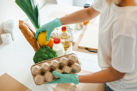 Woman in a white t-shirt is packing food in a cardboard bag. The concept of assistance and volunteering, donationの写真素材