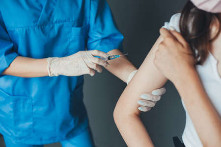 Close up portrait of Doctors hands making a vaccine in the shoulder of patient. Adult immunization,...