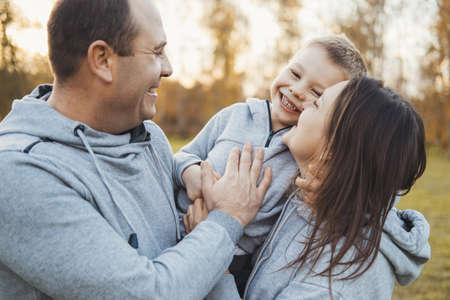 Family of three members having fun together outdoor. Walking in park. Smiling man. Family day.