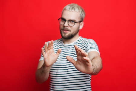 Man wearing eyeglasses standing over red background moving away hands palms showing refusal sign. Stop and forbidden.の写真素材