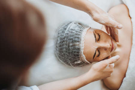 Close-up portrait of a client receiving cleansing peeling at the beauty salon. Beauty face. Cosmetology beauty procedure. Dermatology, cosmetology.の写真素材
