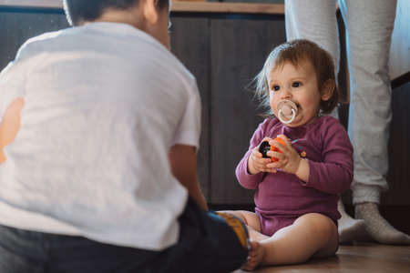 Brother and baby-sister playing with toys on the floor at home. Kids play. Family time.の写真素材