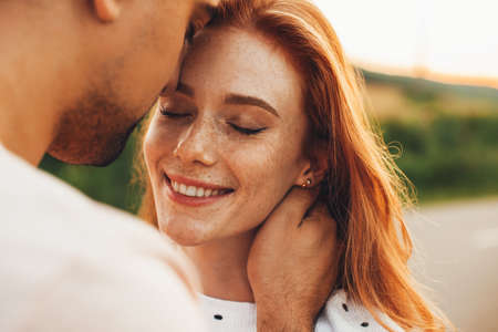 A happy couple in love posing. Wheat field. Freckled face. Pretty young family. Natural beauty.