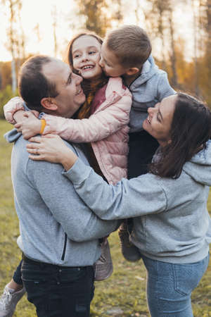 Photo of a family standing together in the park, posing while looking at each other. Happy people.の写真素材