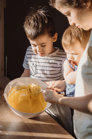 Mother teaching her son mixing dough for cake. Family having time together. Family weekend.の写真素材
