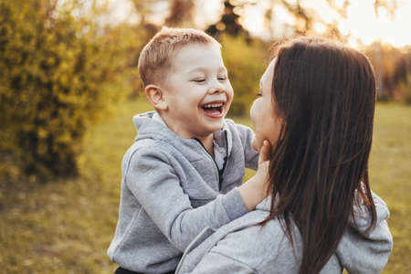 Portrait of a boy happily spending time with his mother in the park. Modern lifestyle. Family care. Smiling happy child.の写真素材