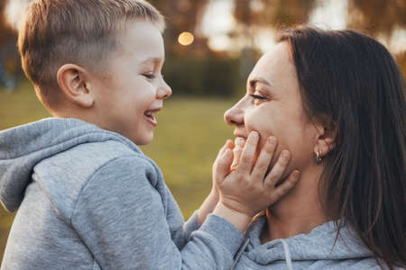 View from one side of a son with his mother looking into each others eyes, smiling. Happy family leisure. Smiling happy child. Family care.の写真素材