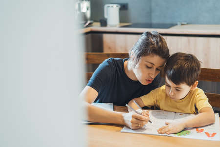 Mother helping son doing homework at home. Parent helping child. Schoolboy.の写真素材
