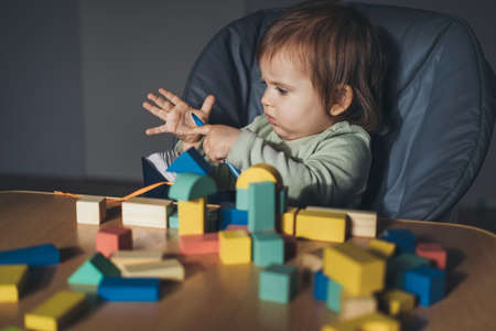 Baby girl playing with connecting toy cubes at home. Children education. Wooden toys. Kids play. Wooden desk, table.の写真素材