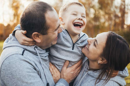 Close-up ortrait of happy family with one kid posing outdoors in public park. Happy people together. Parents and children.の写真素材