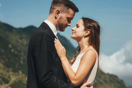 Side view portrait of a groom and a bride posing in nature, looking at each other with love. Beautiful portrait of newlywed.の写真素材