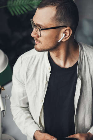 Close-up portrait of an man photographer standing at desk working with photo camera and looking...