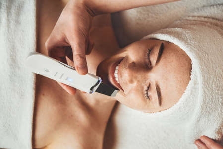 Young woman getting ultrasonic peel skin at cosmetology clinic. Aesthetic cosmetology, face care. Skin care.の写真素材