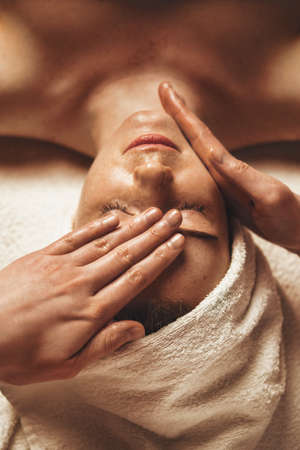 Relaxed female patient receiving massaging face treatment. Beauty face. Beautiful young girl. Body care.の写真素材