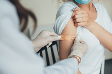 Doctor in rubber protective gloves putting adhesive bandage on patients arm after vaccination. Pandemic prevention. virus vaccination. virus pandemic protection concept. Healthcare people.の写真素材