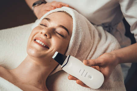 Close up photo of a woman in cosmetological clinic getting ultrasonic peeling face procedure. Medical treatment. Girl facial treatment.の写真素材