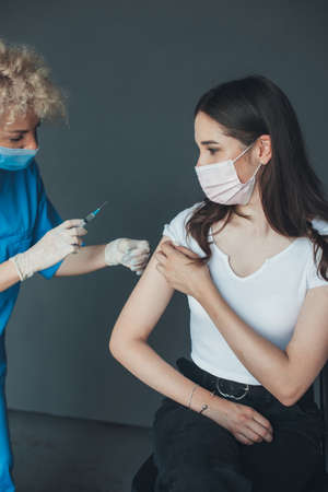 Female doctor in protective mask prepairing for injecting vaccine against coronavirus into patients arm. Medical healthcare concept. Coronavirus vaccination. Pandemic prevention. Healthcare people.の写真素材