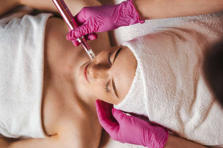 Top view of a woman getting facial mesotherapy treatment by professional dermatologist. Skin beauty...