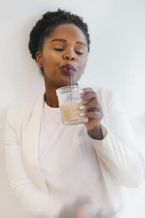 Beautiful woman drinking cold icy coffee in cafe from a glass jar. Healthy lifestyle. Healthy drink.の写真素材