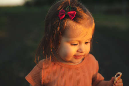 Smiling baby girl walking in the field at sunny summer evening. Smiling girl. Smiling happy child....