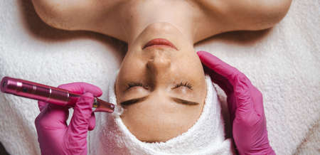 The cosmetologist's hands making the procedure Microdermabrasion of the woman's face. Health care, beauty treatment. Skin treatment. Medical equipment. Cosmetic beauty spa salon. Beauty face. Professional beauty salon.の写真素材