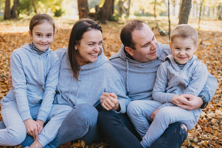 The family sitting on the leaves in the autumn forest and enjoying the autumn colors.の写真素材