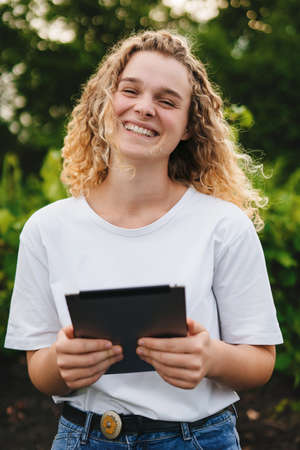 Employed woman portrait with curly hair smiling looking at camera, recording the growing of grapes in their fields on a tablet. Smart farming and precision agriculture. Farmer field. Data analysis.の写真素材