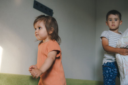 Two children standing on the couch waiting for the right moment to start the pillow fight, in the...