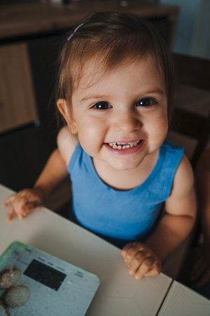 Baby adorable girl looking into the camera and smiling while waiting for the ingredients to be weighed. Spring traditions and cooking. A cute little funny girlの写真素材