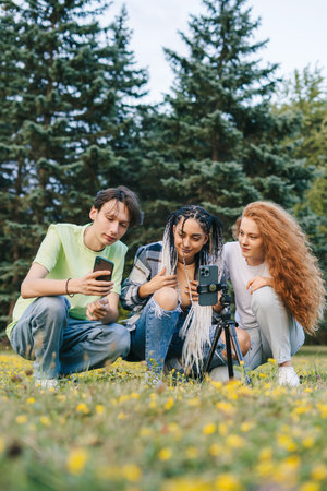 Group of friends using mobile phones outdoors in city park watching online content. Internet technology. School girls friends. Internet network. Social media app. Youth lifestyle.の写真素材