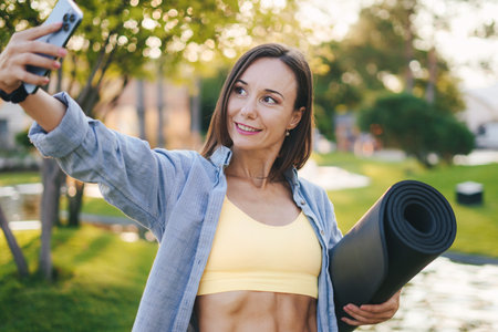 Shot of beautiful sporty woman taking a selfie by her mobile phone after jogging outdoors. People body fit healthy. Fitness workout. Healthy lifestyle.の写真素材