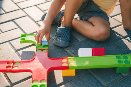 Close-up of a boy playing outside with plastic toys. Railway transportation. Outdoor lifestyle. Early education.の写真素材
