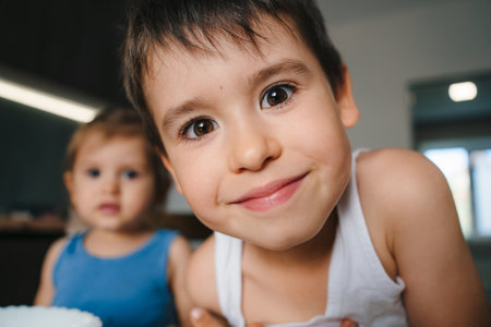 Boy making funny faces at the camera while cooking in the kitchen with his family. Child having fun with helping. Cute funny caucasian kid boy cookingの写真素材