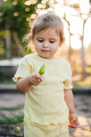 Portrait of an adorable baby girl holding a pepper recently picked from her grandmothers summer garden. Growing fresh organic natural food and vegetablesの写真素材