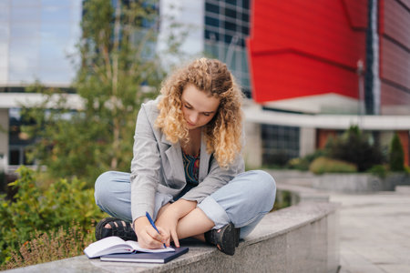 Caucasian woman university student with notebooks learning at campus yard. Beauty portrait. Young woman face portrait. Fashion model. People lifestyle.の写真素材